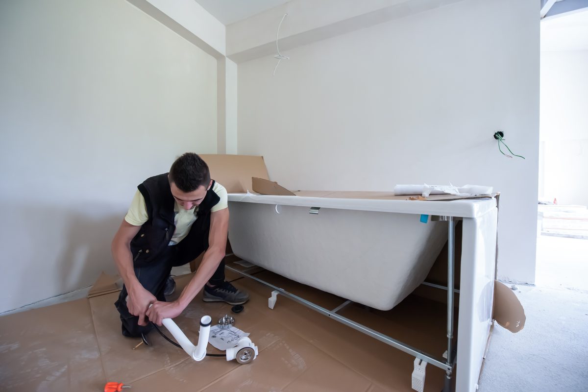 Bath standing on its frame while the waste and overflow kit is assembled