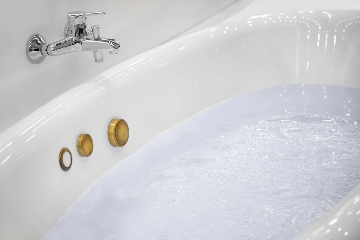 Bath filled with water with a mixer tap at one end