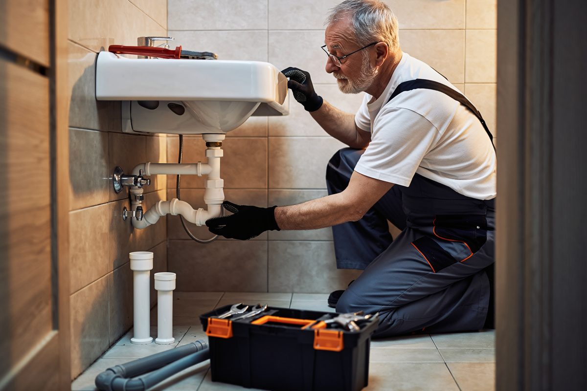 Plumber working on the pipework under a bathroom basin