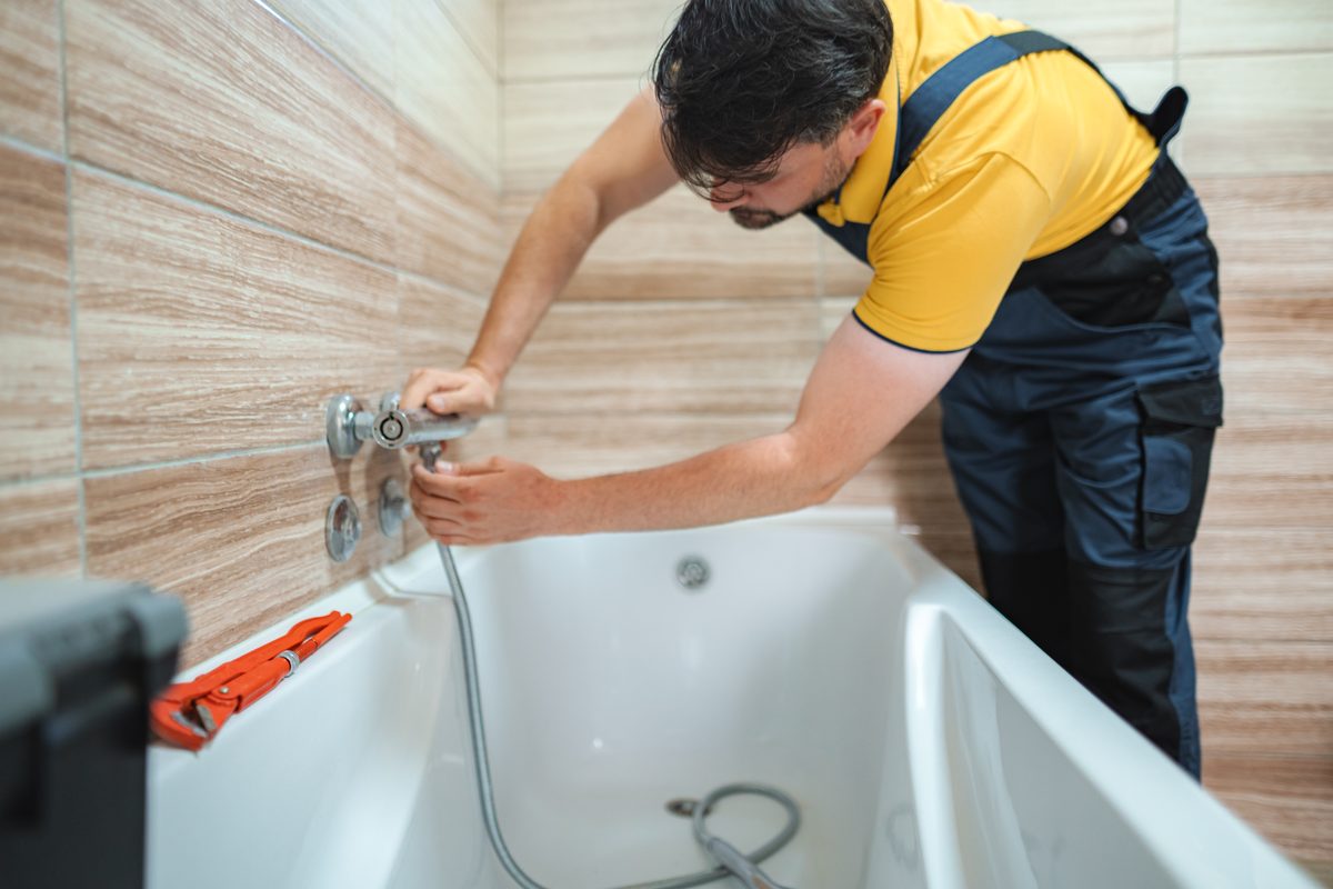 Plumber fitting a tap to a bath