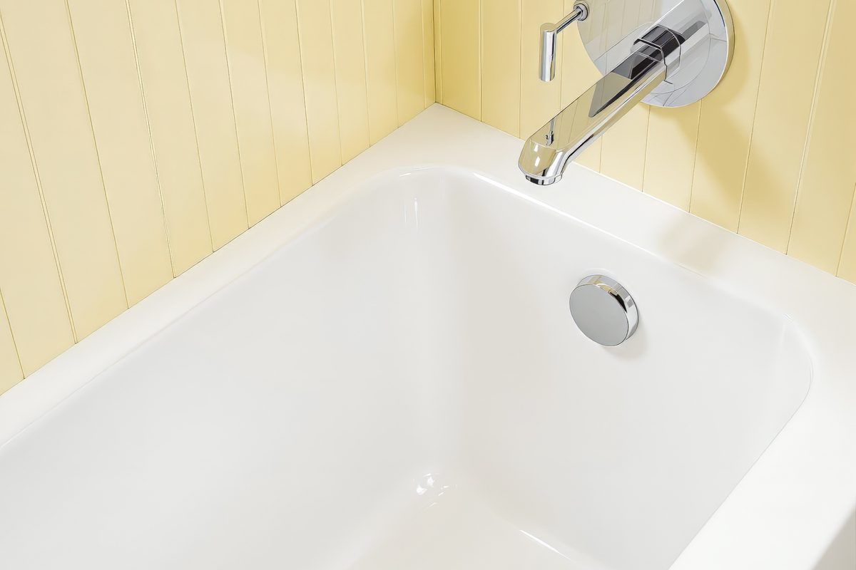Clean white soaking tub with a slim bath mixer alongside